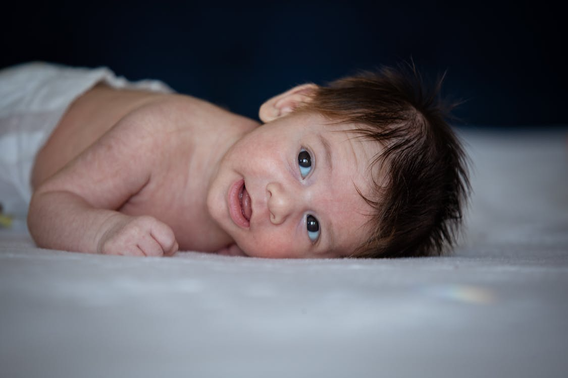 A new born baby lying on white sheets